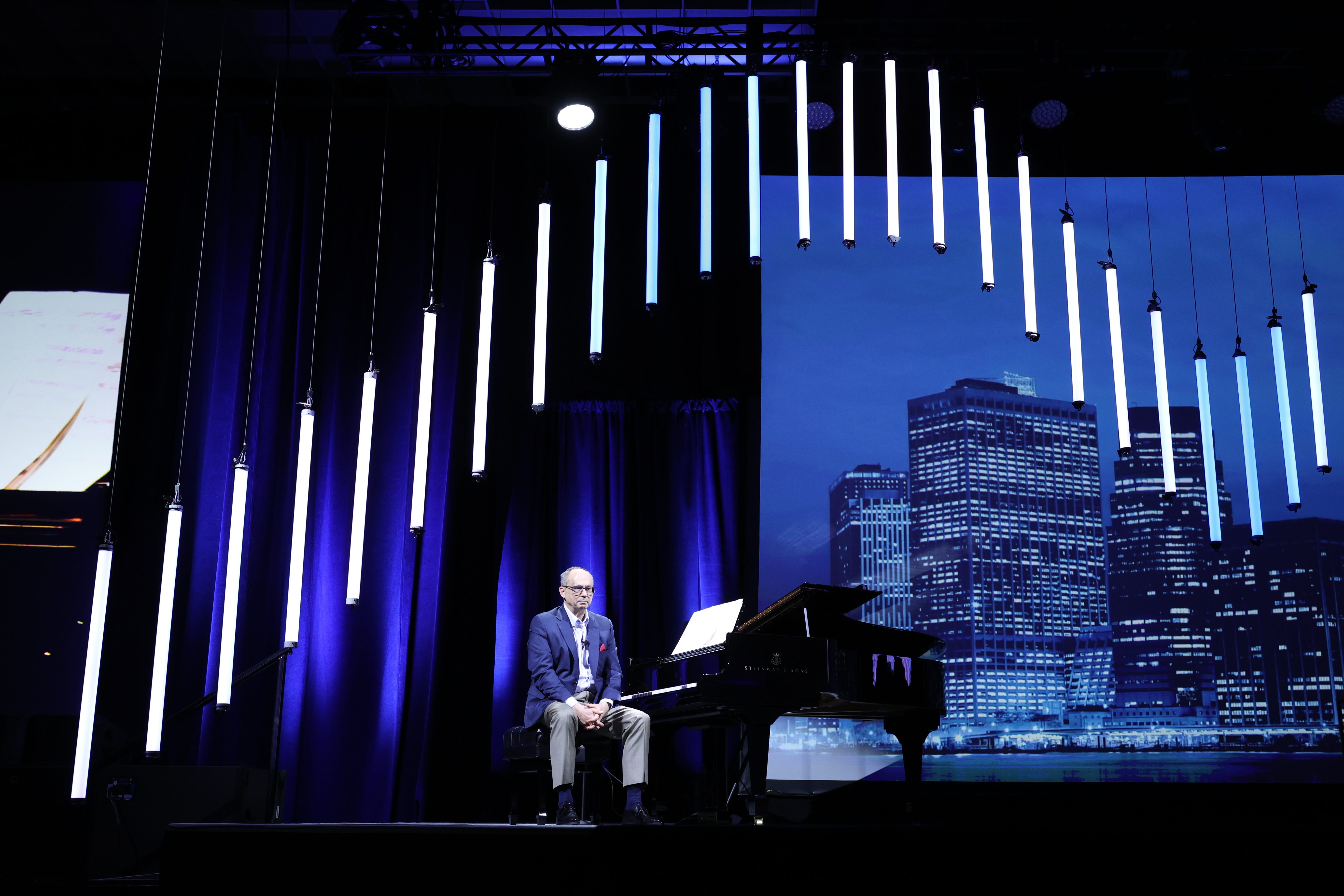 Jim Holthouser sits at a piano onstage.