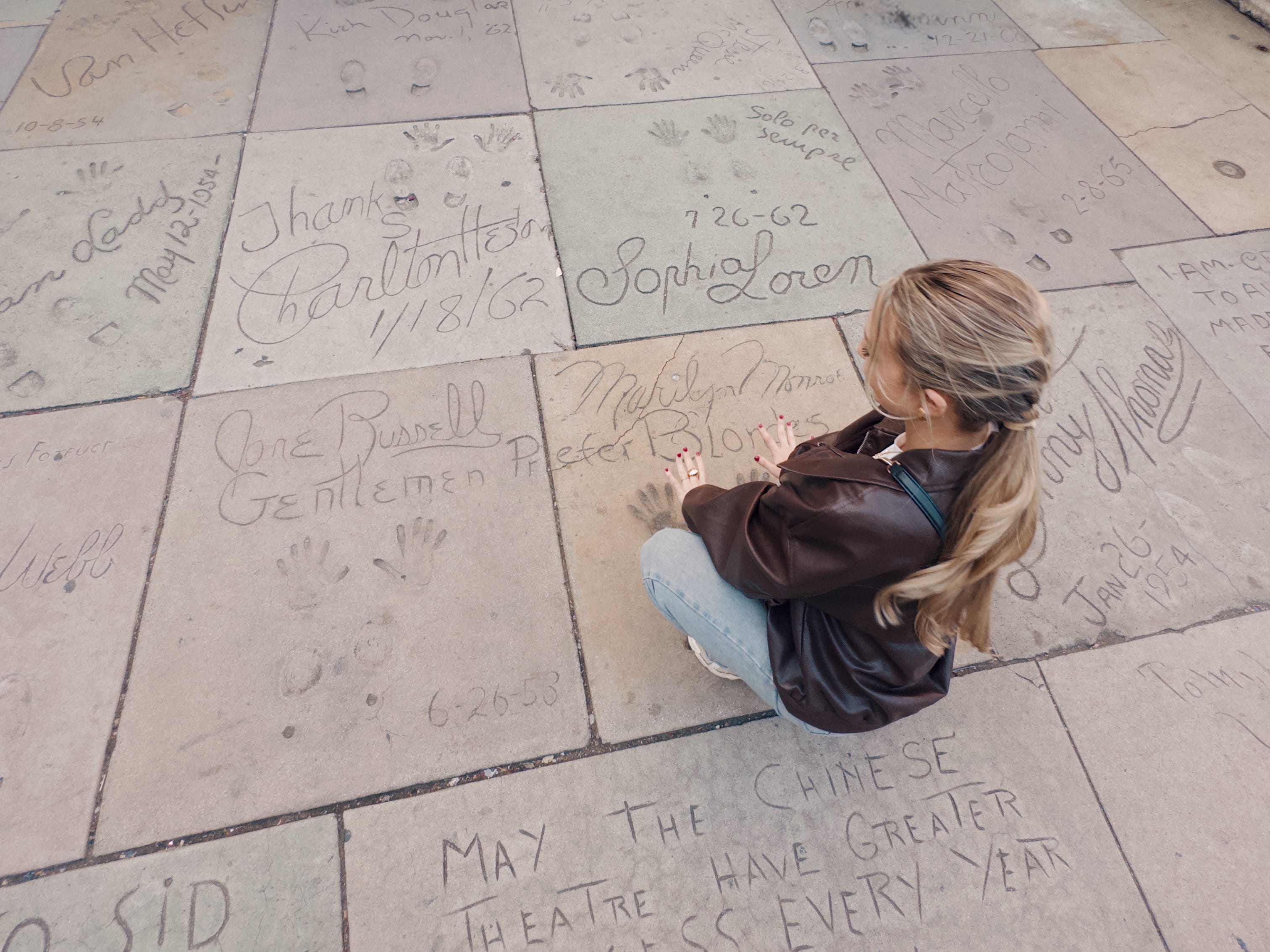 Chloe places both hands on Marilyn Monroe's cemented handprints at the TCL Chinese Theater.