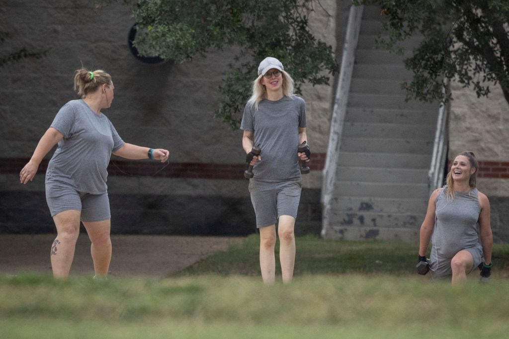 Elizabeth Holmes walking on a track at a federal prison camp, carrying hand weights.