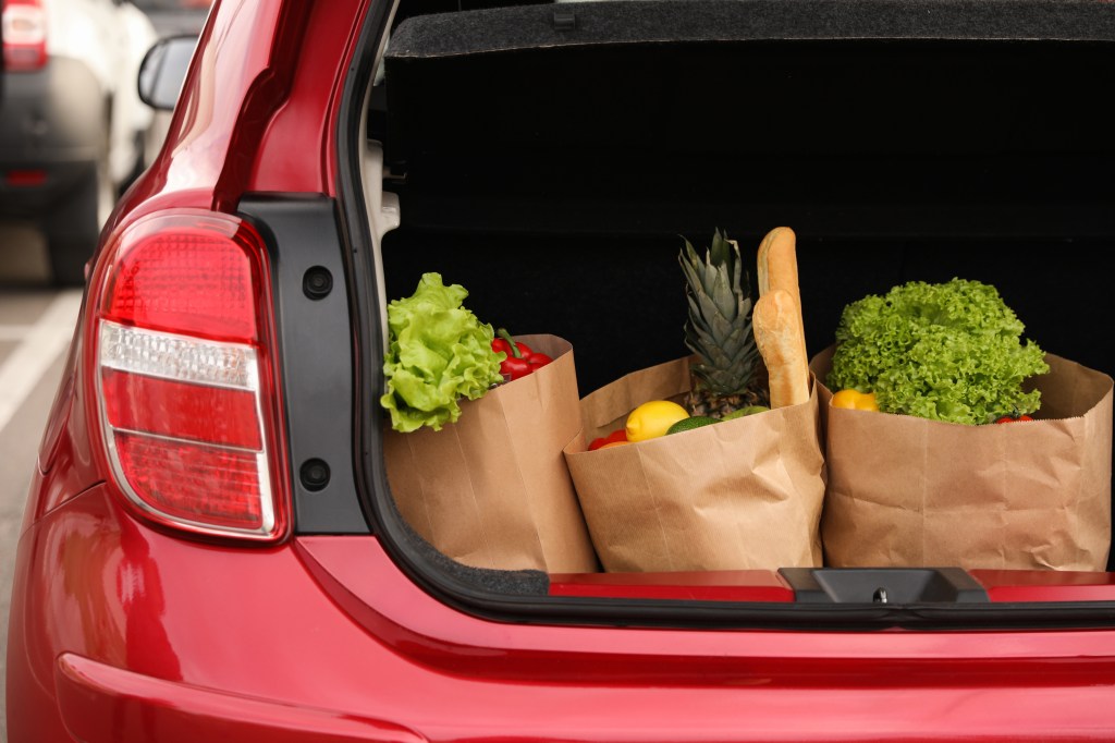 Grocery bags full of produce in a car trunk.