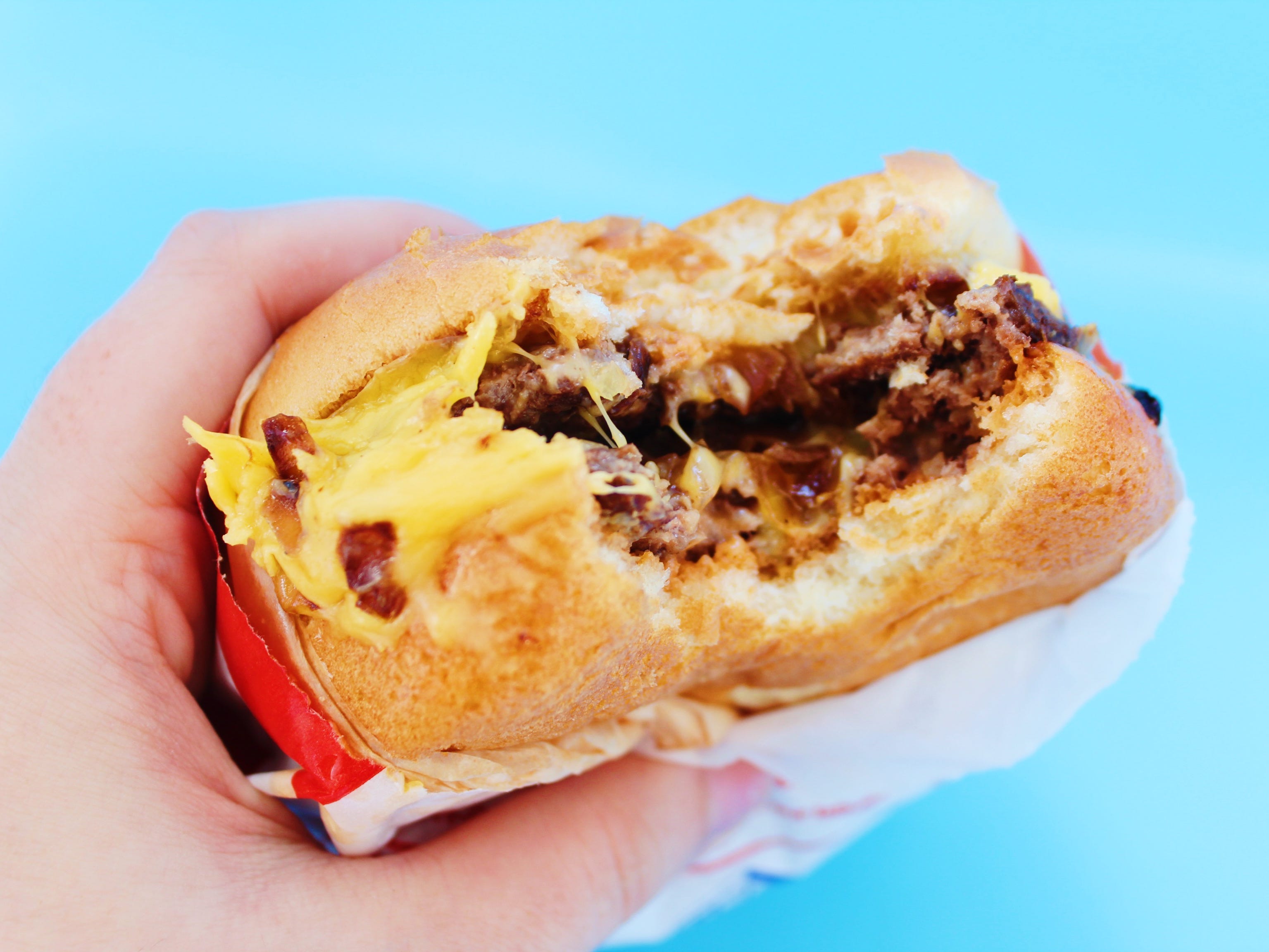 bitten into in n out double double on blue background