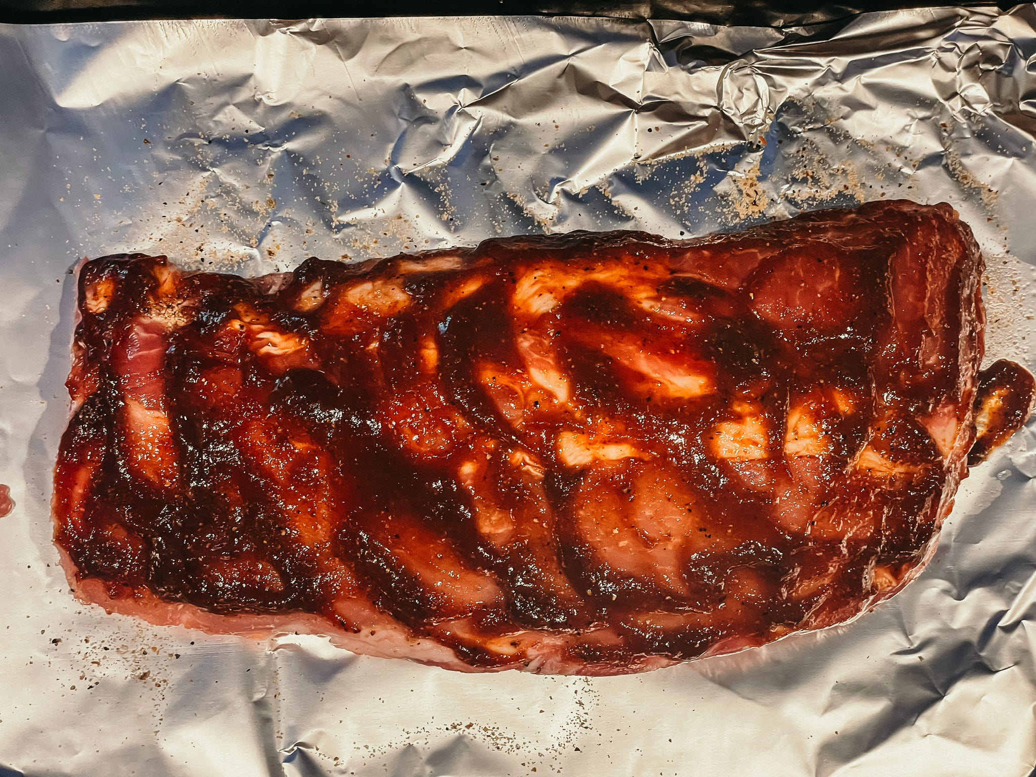 raw rack of ribs covered in seasoning and sauce