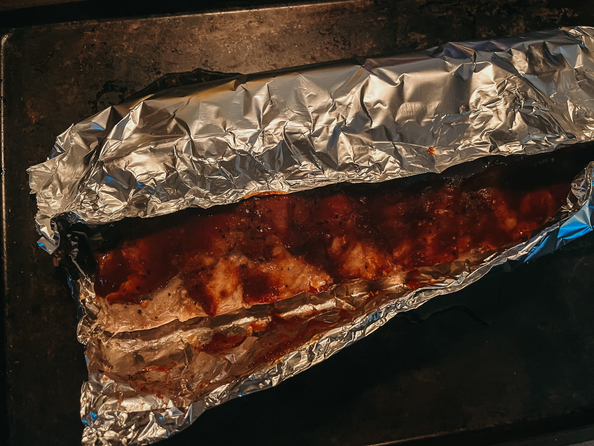 barbecue sauce on ribs wrapped in foil
