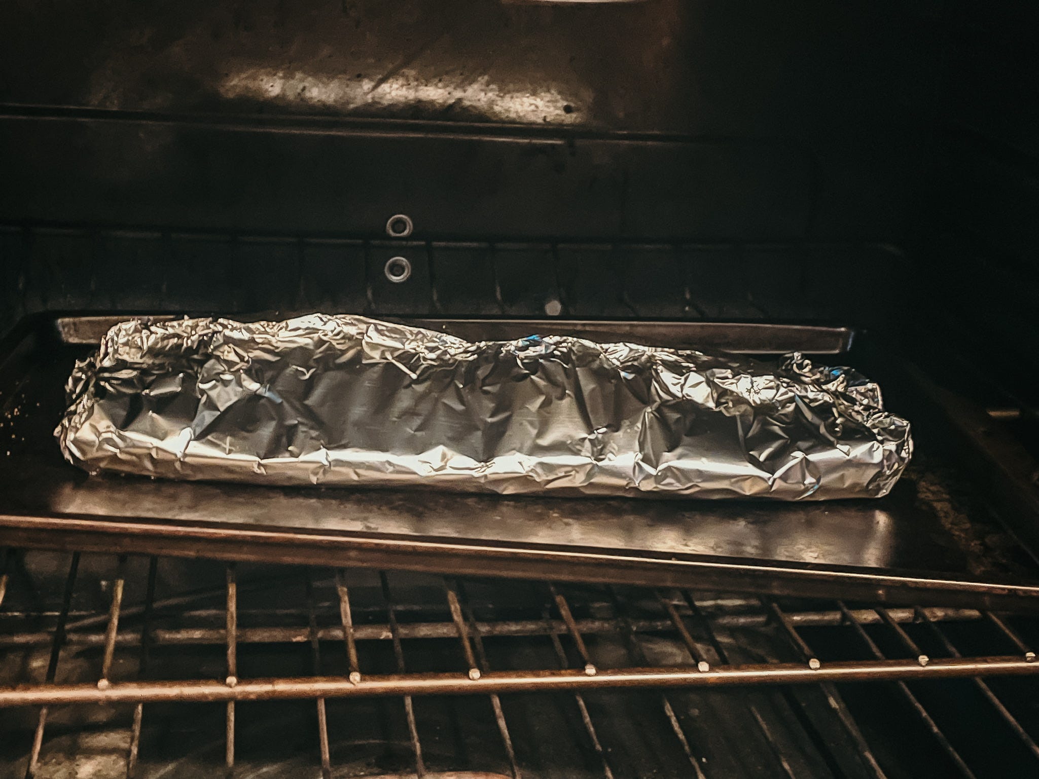 rack of ribs covered in foil in an oven