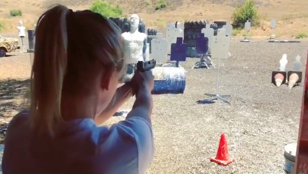 Woman shooting a handgun at a target range.