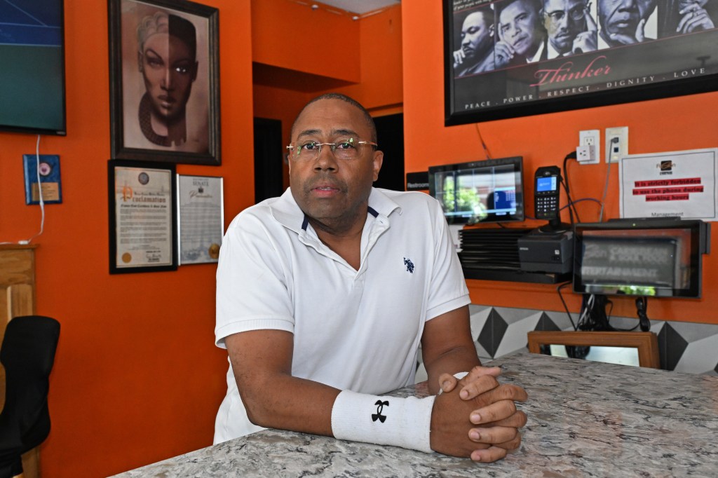 Andrew Walcott, owner of Fusion East Caribbean restaurant, sitting at a counter in his restaurant.