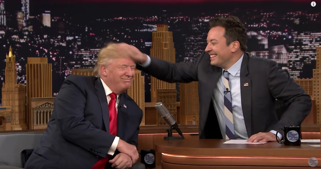 Donald Trump in a black suit and red tie, Jimmy Fallon in a grey suit and grey striped tie.