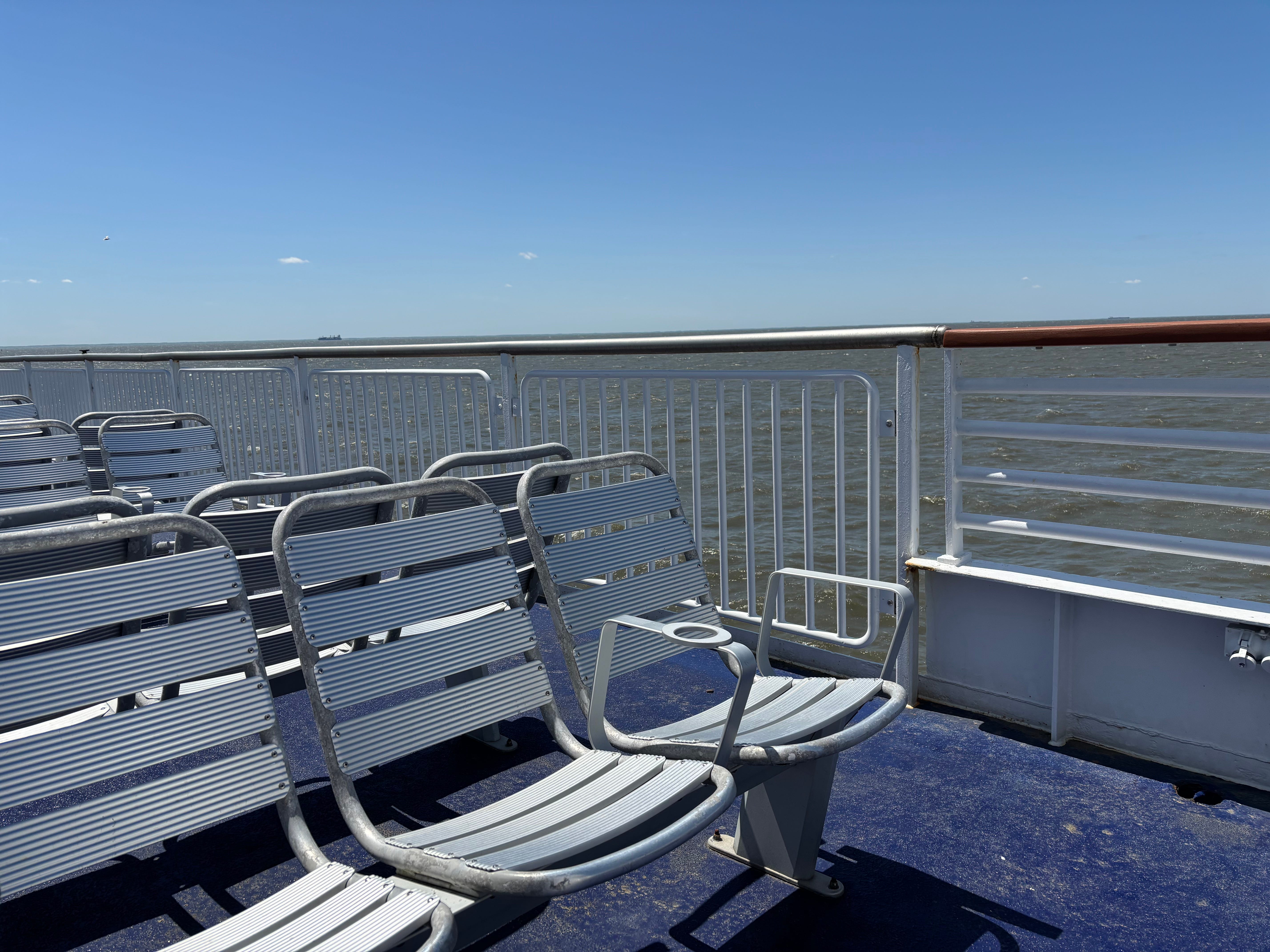Empty metal seats on an outdoor ferry deck..
