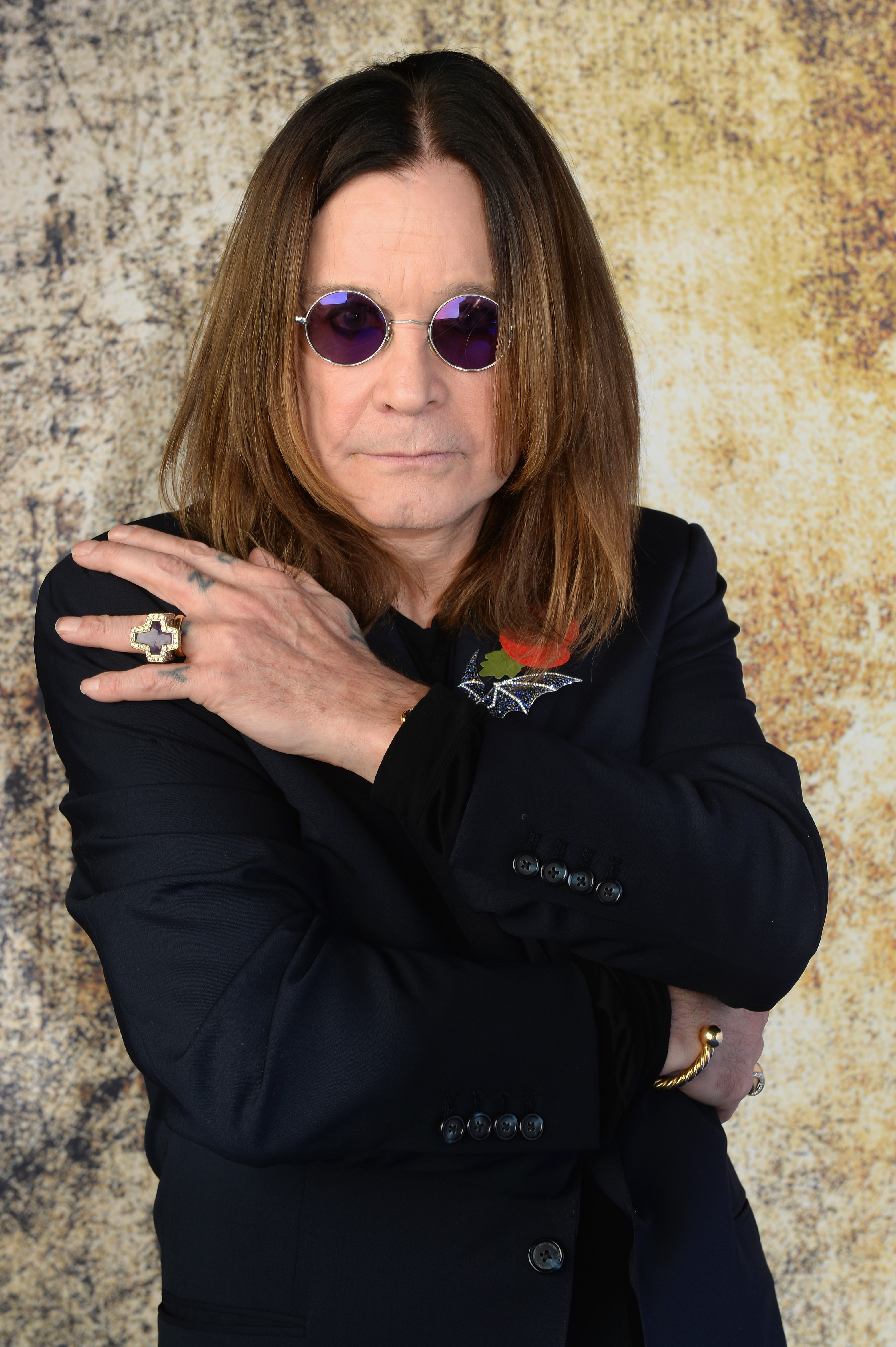 Ozzy Osbourne crosses his arms over his chest. 