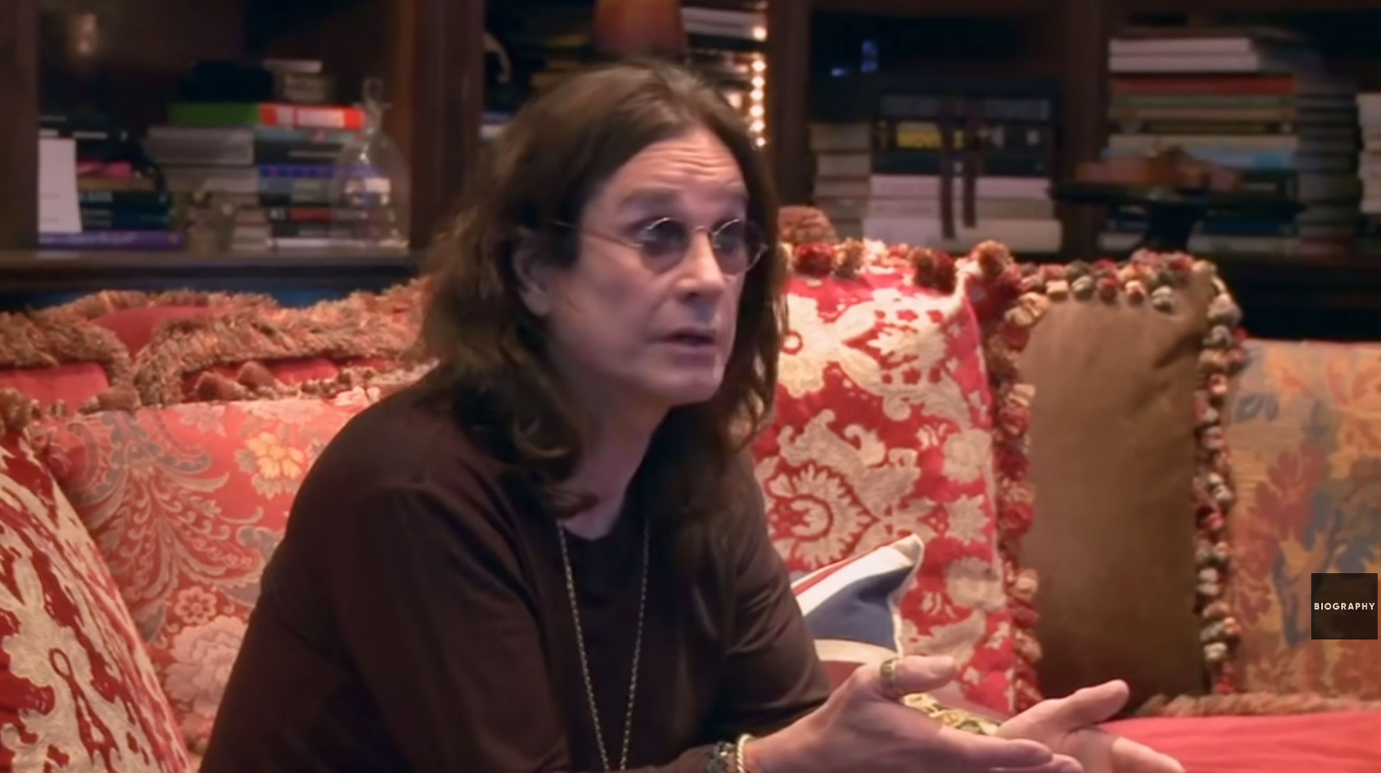 Ozzy Osbourne sits on a couch. 
