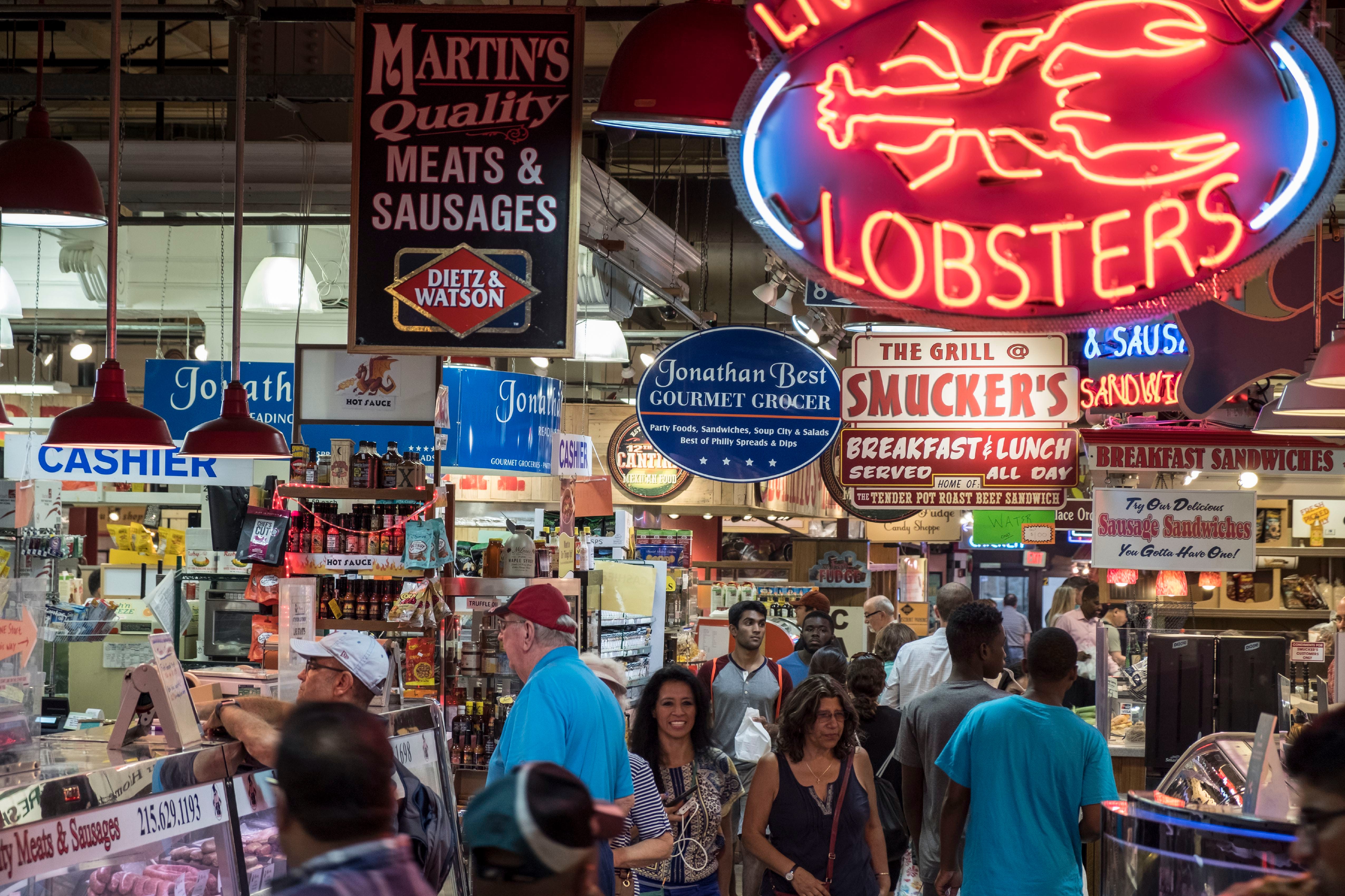 Restaurant and food signs and crowds of people inside Reading Terminal Market
