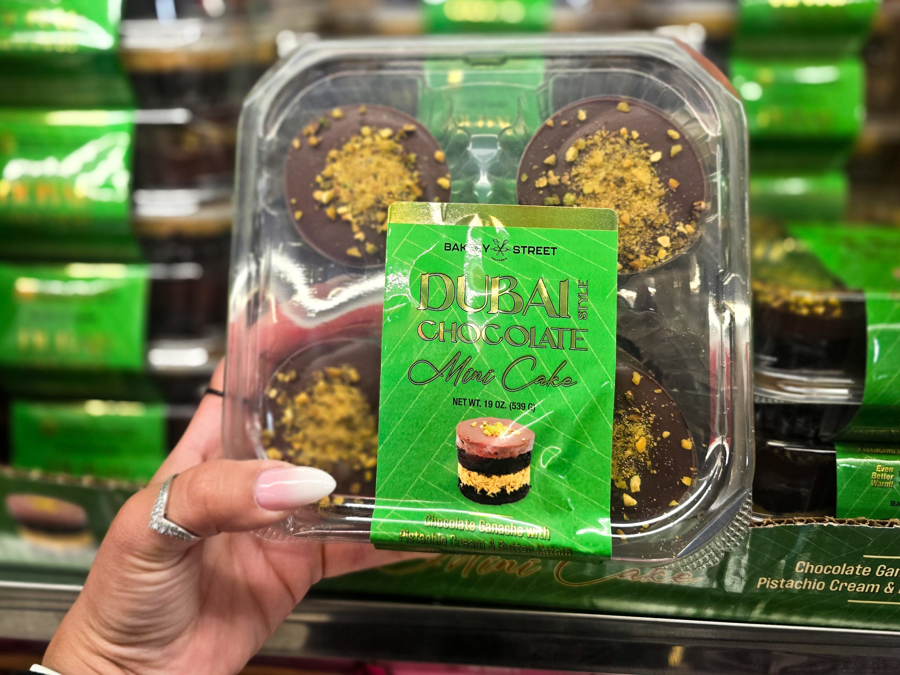 A hand holding a package of Bakery Street Dubai chocolate mini cakes.