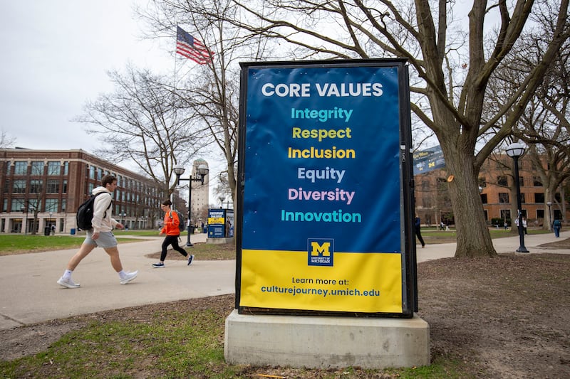 ANN ARBOR, MICHIGAN - APRIL 3: University of Michigan students walk on the UM campus next to signage displaying the University's