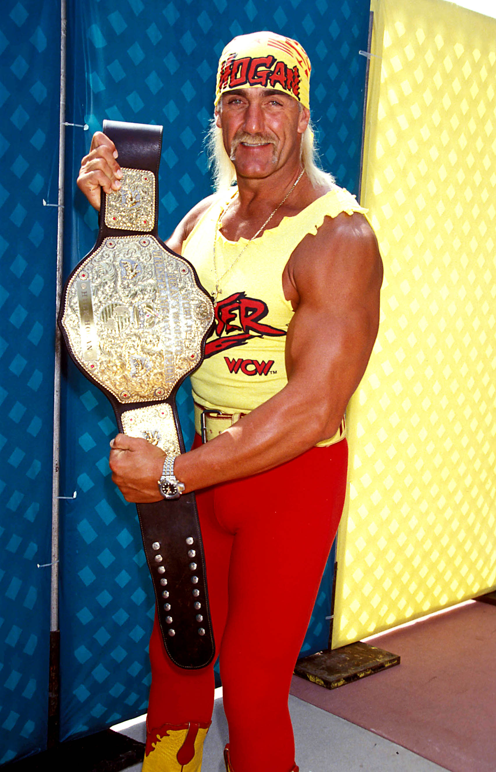 Hulk Hogan holding up a wrestling belt.