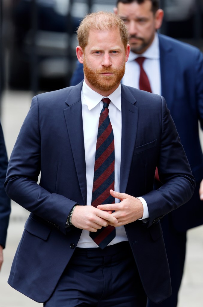 Prince Harry walking in a navy blue suit.