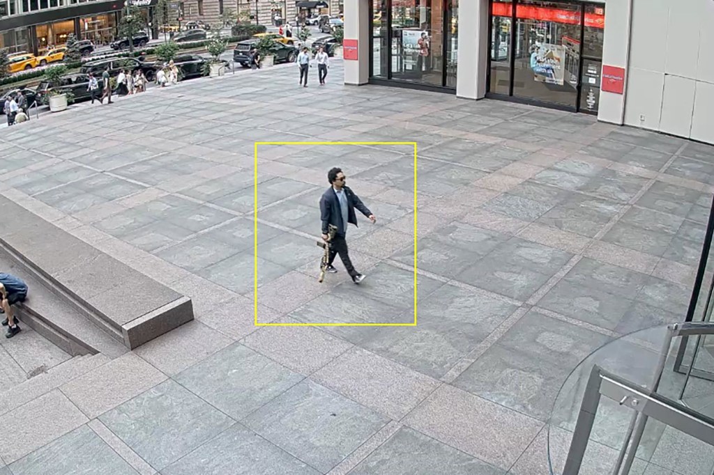 Security camera footage of a man carrying a rifle.