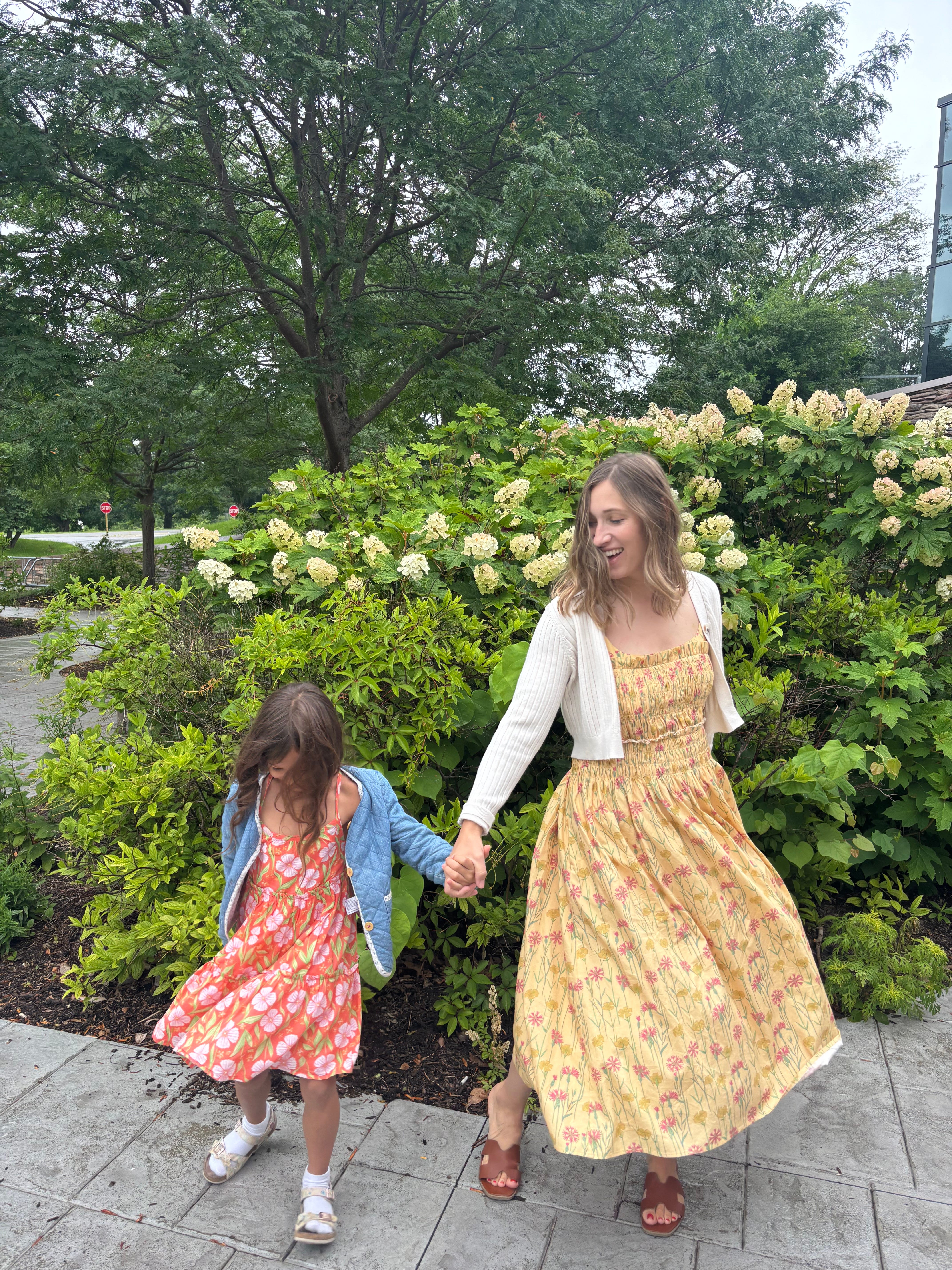 The author and her daughter wearing sundresses and spinning in front of plants.
