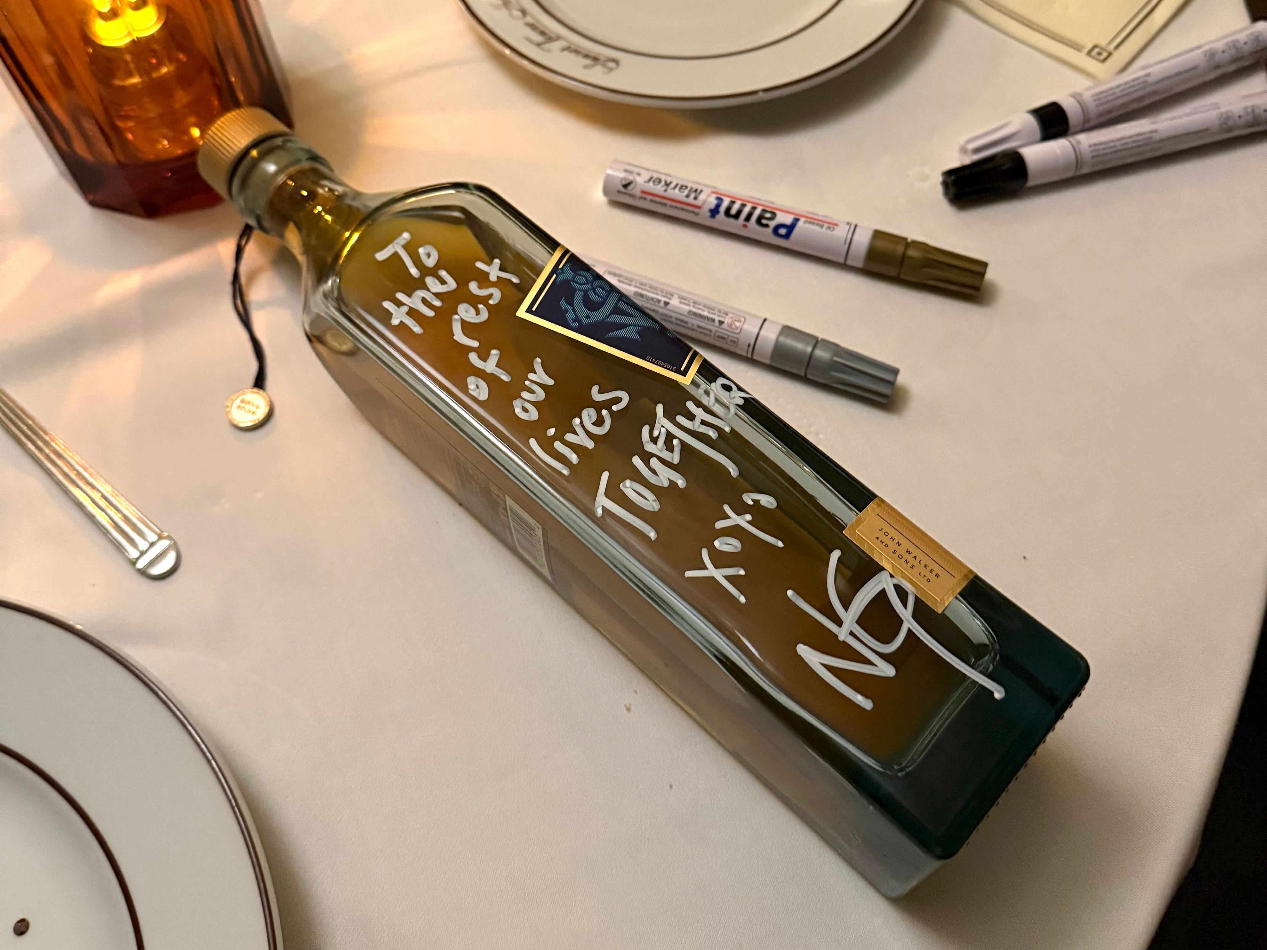 A bottle of scotch with a hand-written note from a newly-engaged couple.