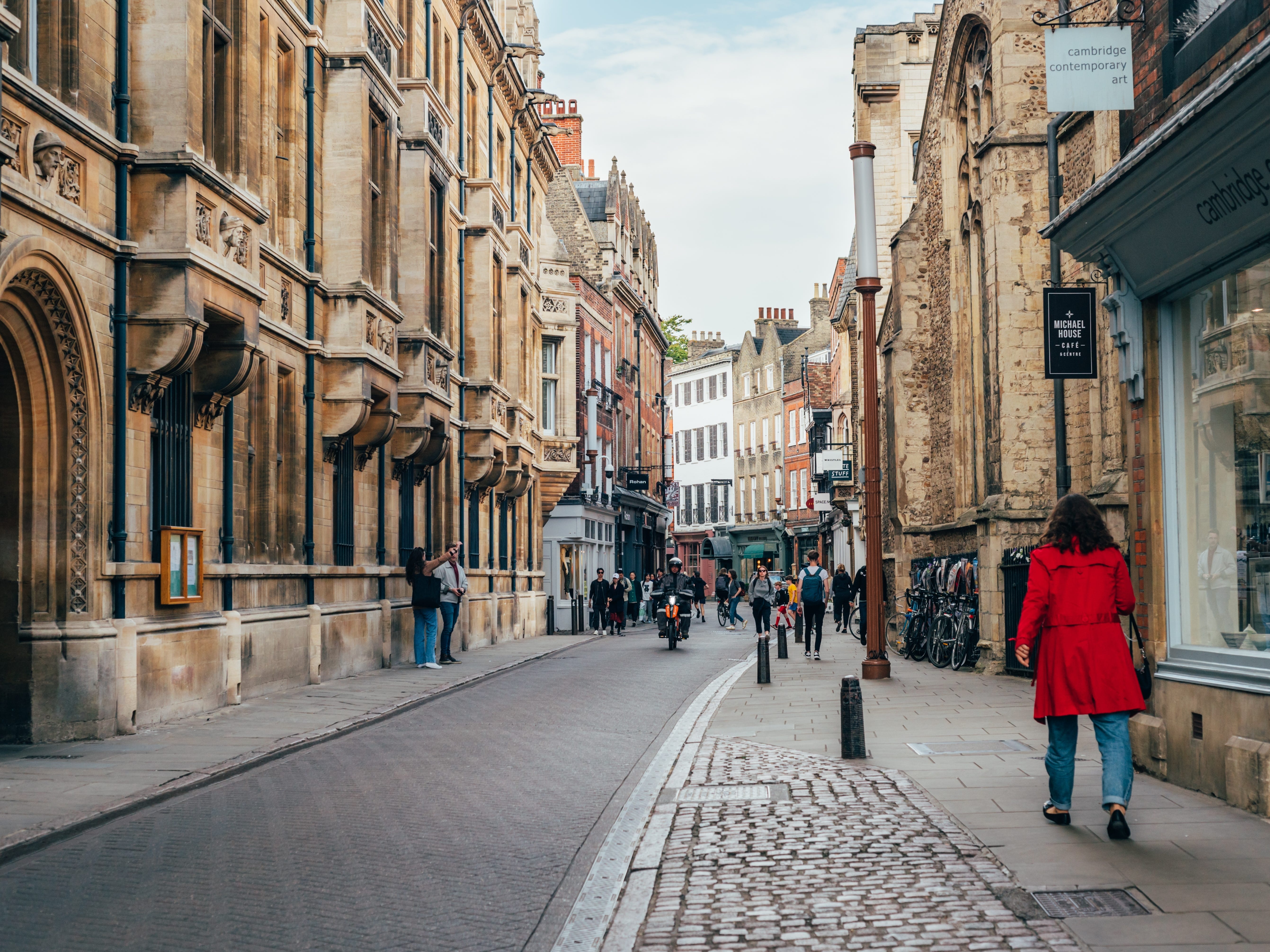 People walking down a narrow street lined with shops.