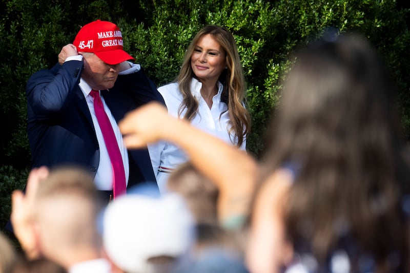 First Lady Melania Trump smiles at President Donald Trump as he dons his trademark red "Make America Great Again" hat before greeting members of the military and their families on the South Lawn of the White House in Washington, D.C. on July 4, 2025.