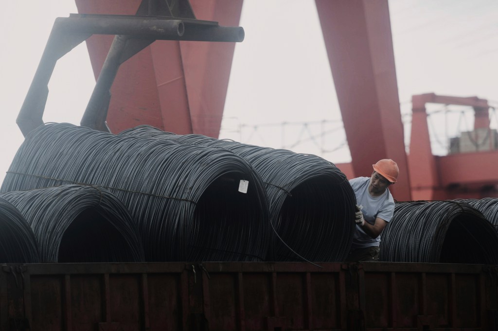 A worker arranges steel rolls on a truck at a steel market in Hangzhou in east China's Zhejiang province on July 7, 2025