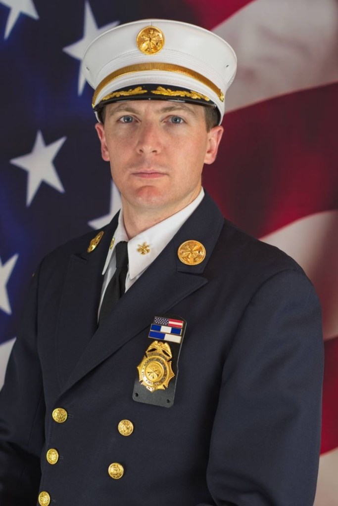 Portrait of a firefighter in uniform against an American flag.