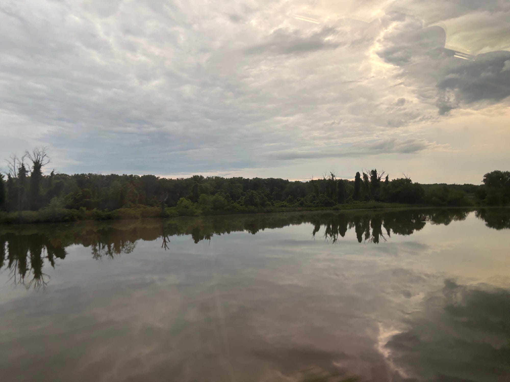 A lake surrounded by trees and overcast clouds.