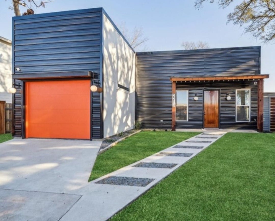 modern style house with orange garage door, wood front door, and black siding