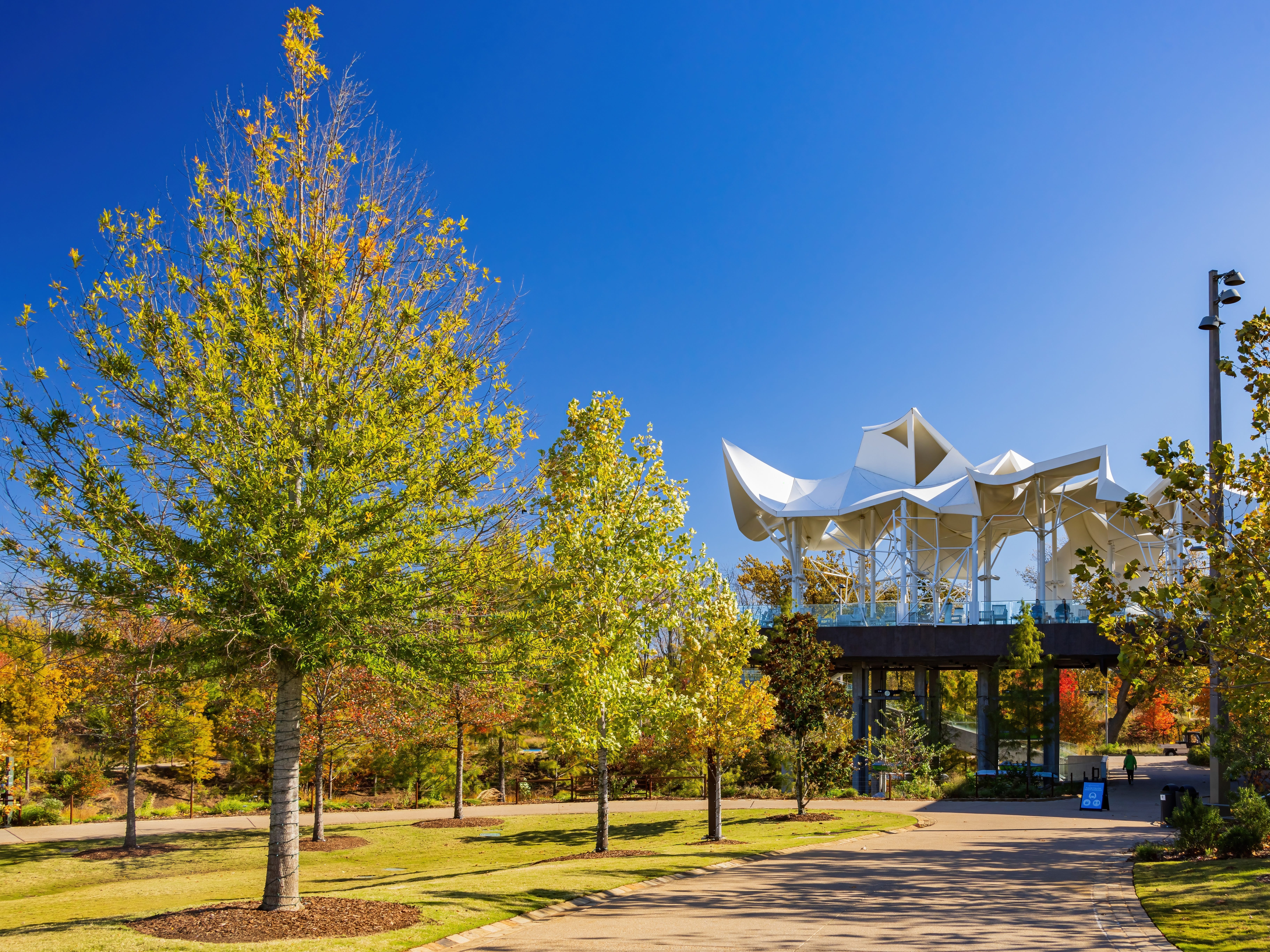 A park with trees, a path, and a two-story structure.