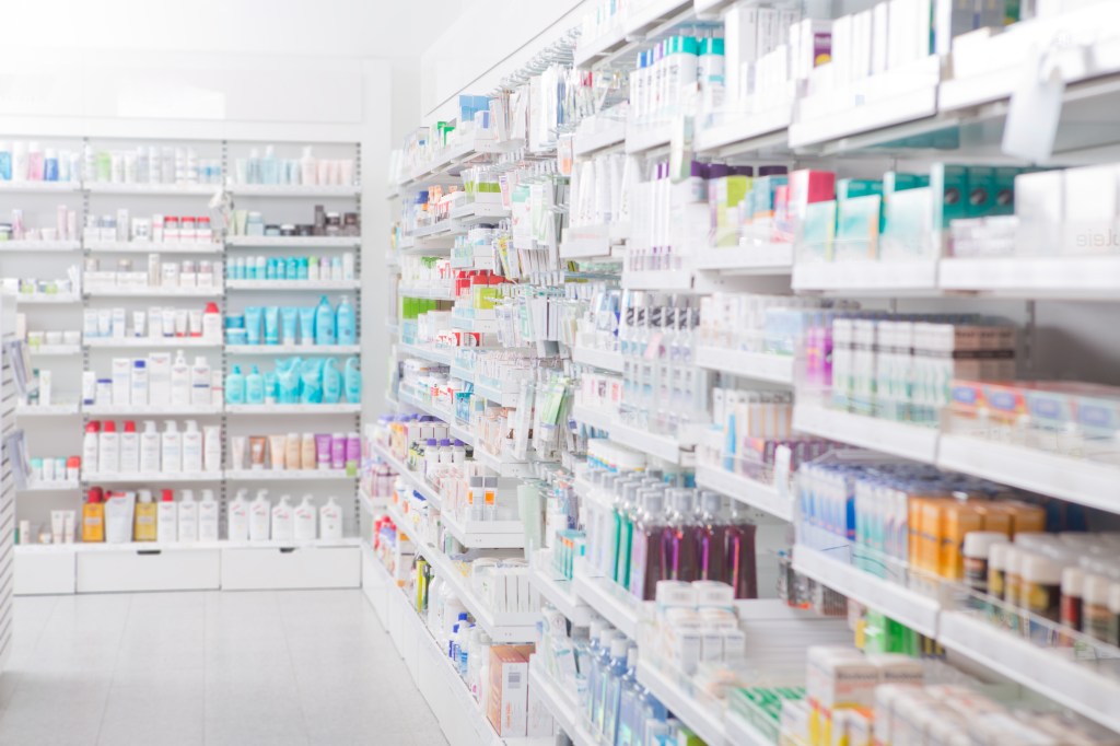 Pharmacy interior with shelves stocked with various medications and health products.