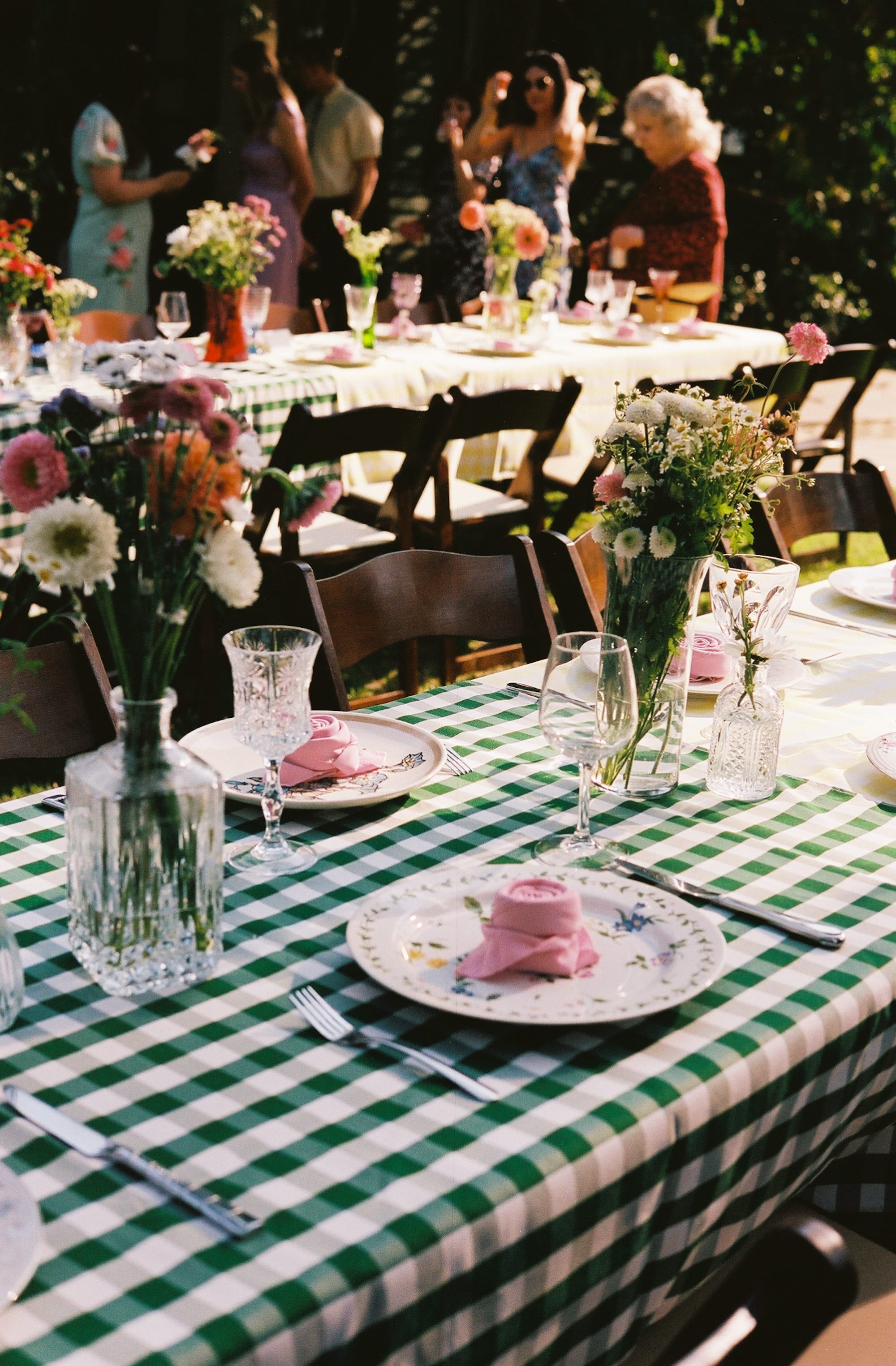 Tables with napkins arranged like flowers on them in a backyard.