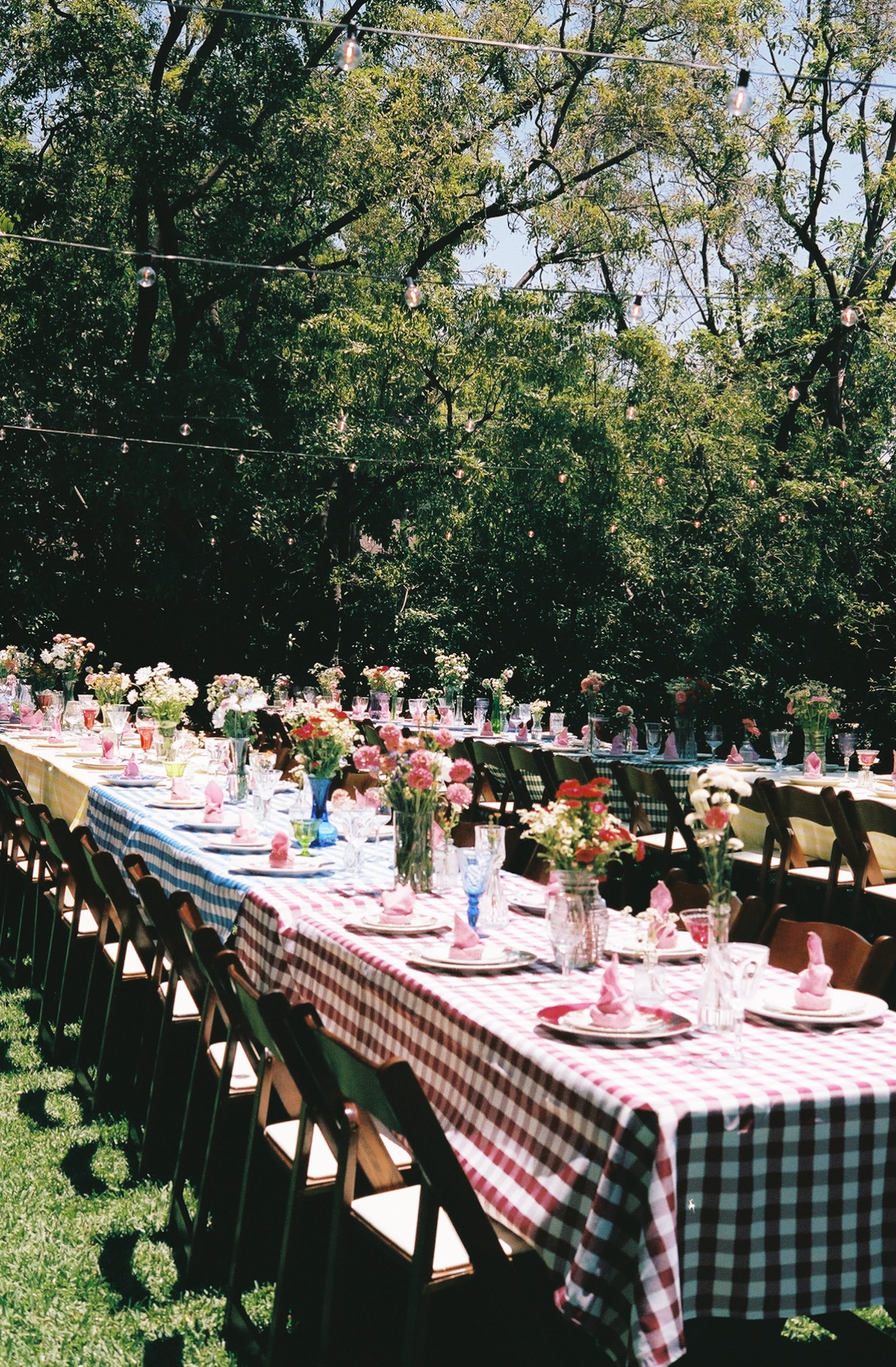 Tables with gingham tablecloths and flower bouquets.