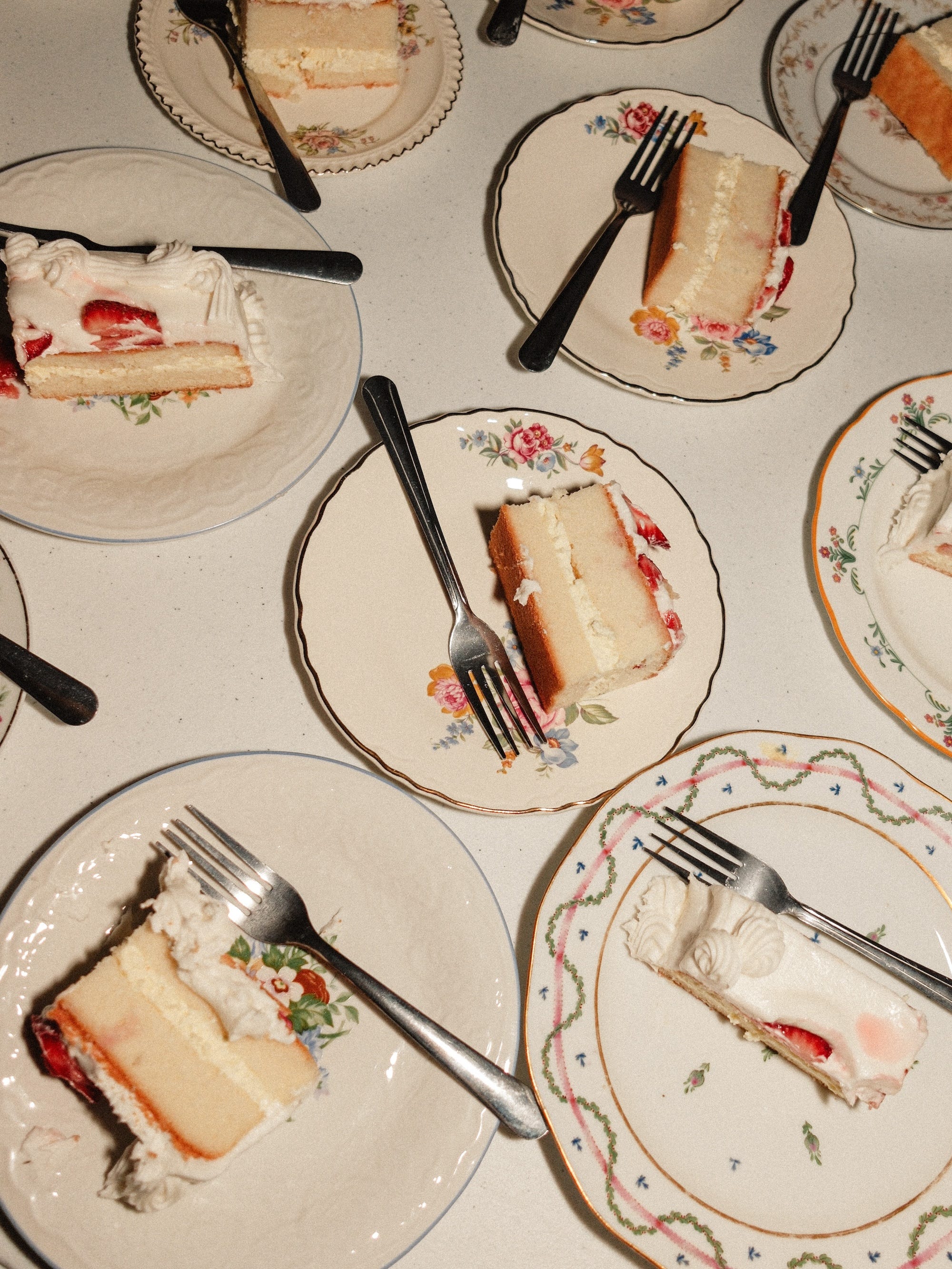 A table with mismatched plates with pieces of cake on it.