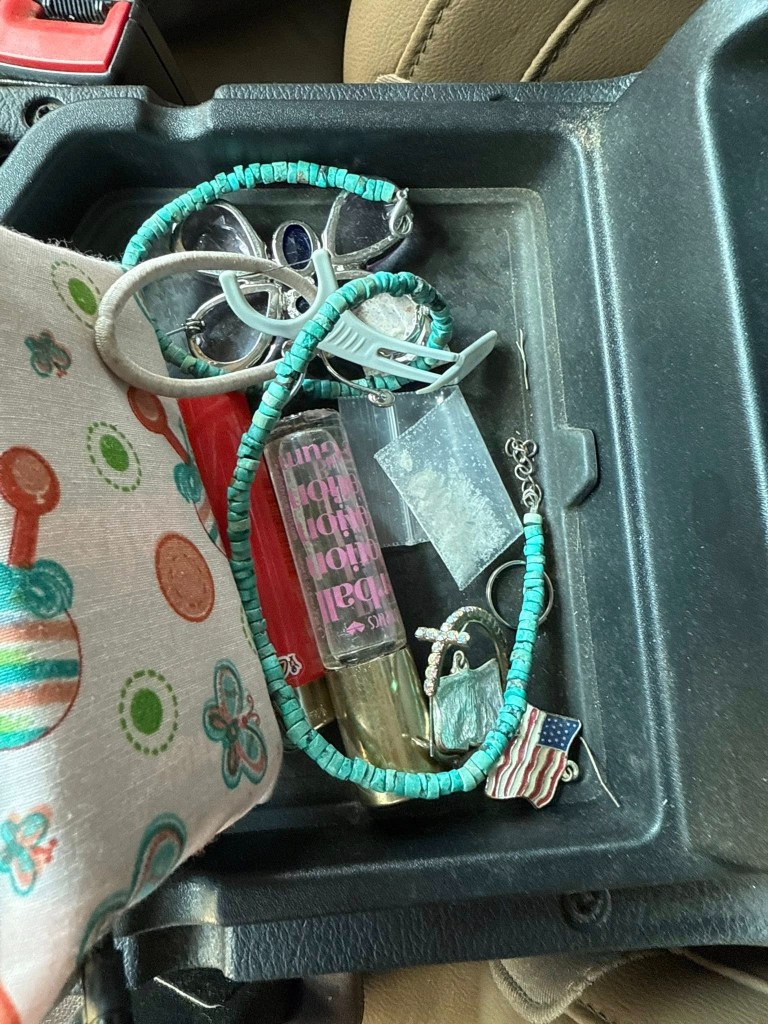 Contents of a vehicle's center console: jewelry, sunglasses, and other personal items.