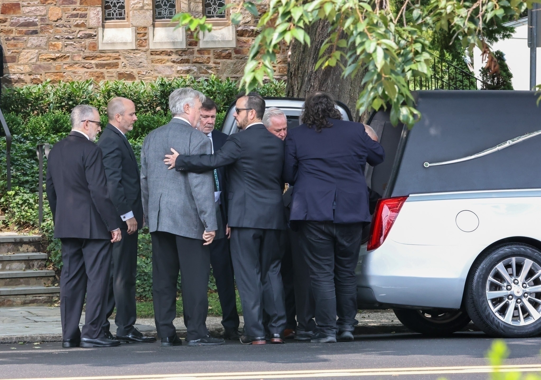 Men standing outside a hearse. 