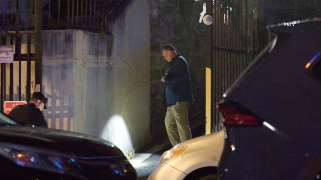 A man standing near a police officer at night.