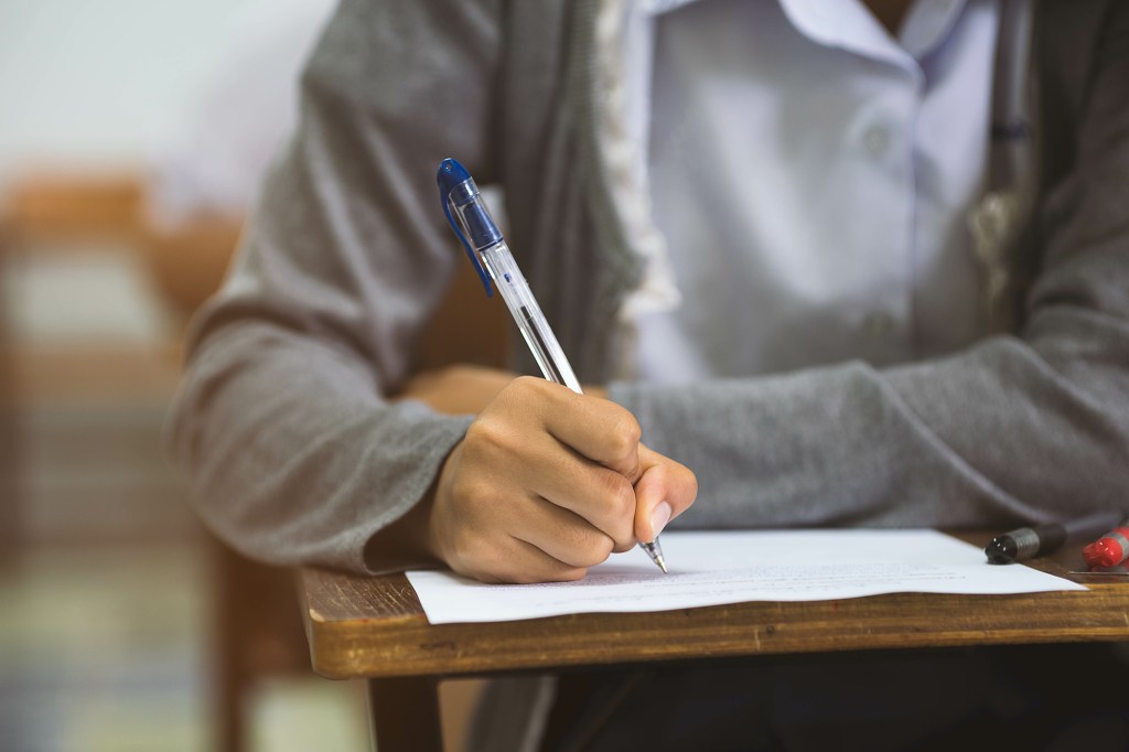 Close-up of a student's hand writing an exam.