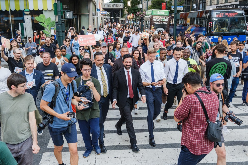 Mayoral candidate Zohran Mamdani participating in a race against a city bus.