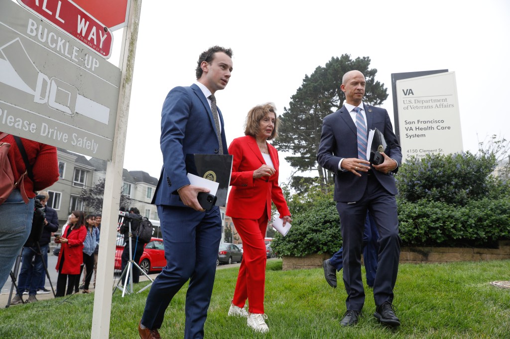 Nancy Pelosi walking with aides at the San Francisco VA Medical Center.