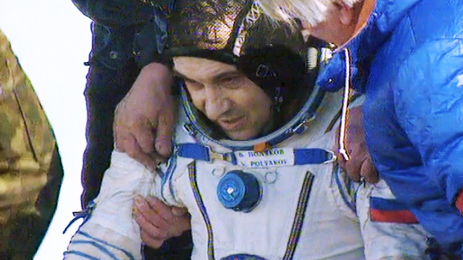 photo of valry polaykov in a white and blue cosmonaut space suit