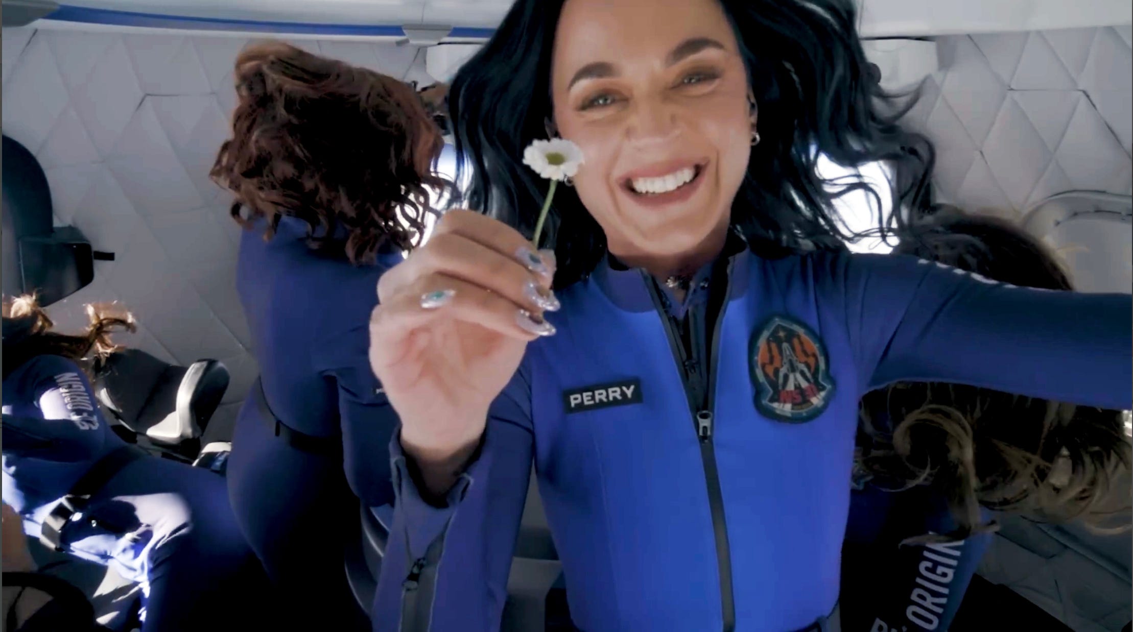 Katy Perry in space holding a white flower