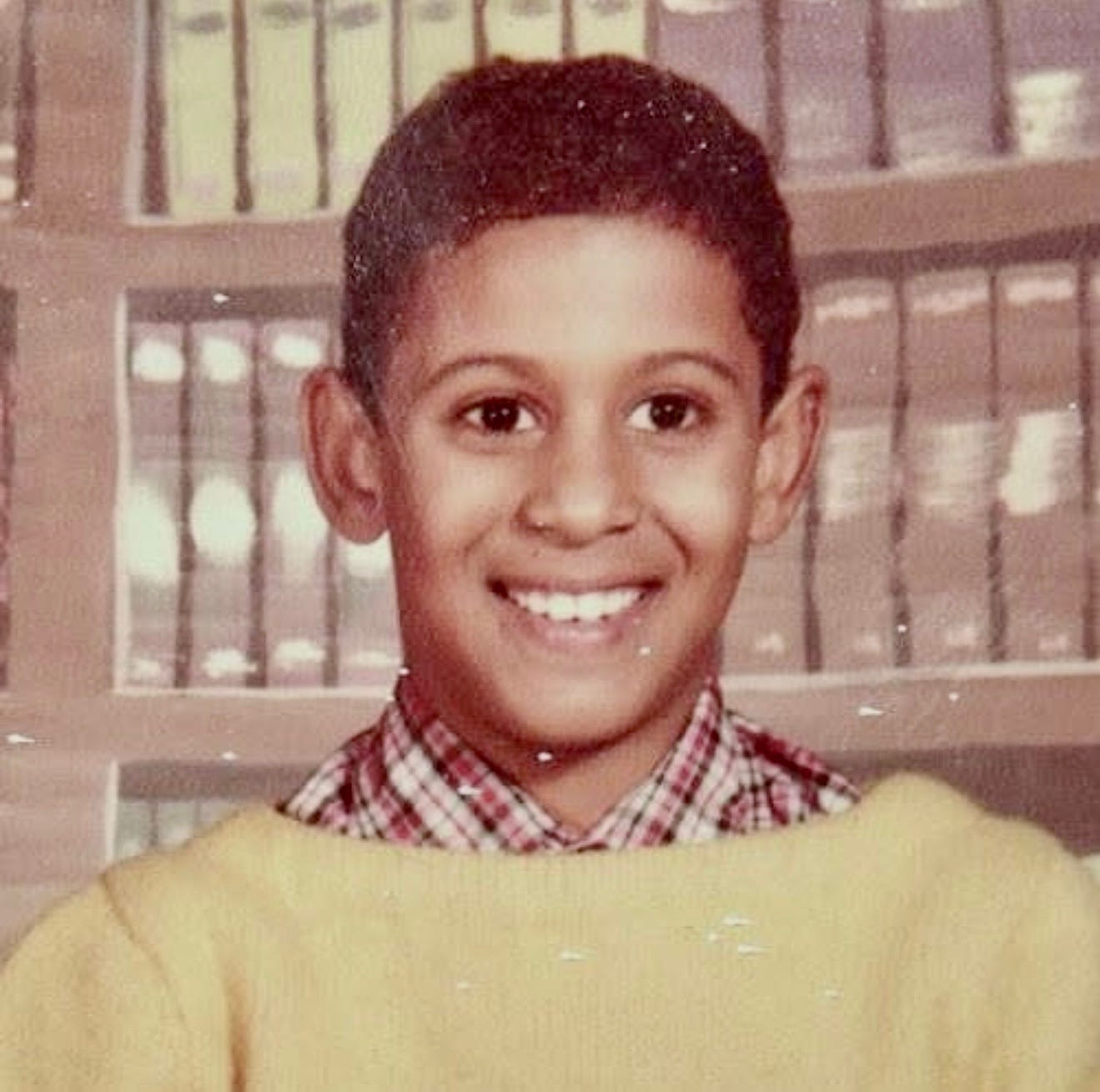A school picture where a boy is wearing a yellow sweater over a button-up shirt.
