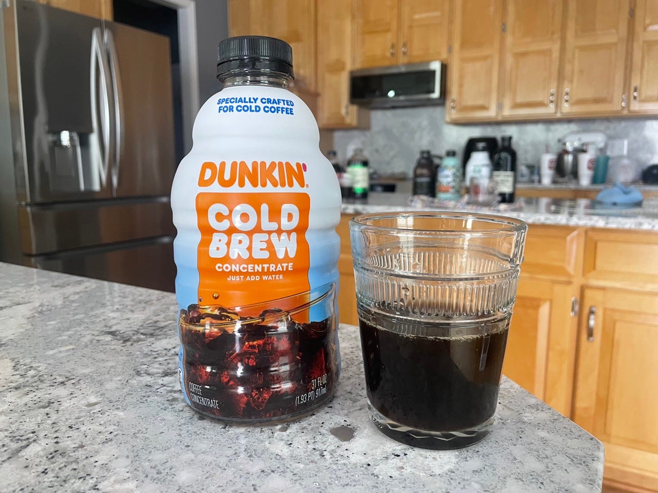 Dunkin cold brew bottle next to glass of cold brew