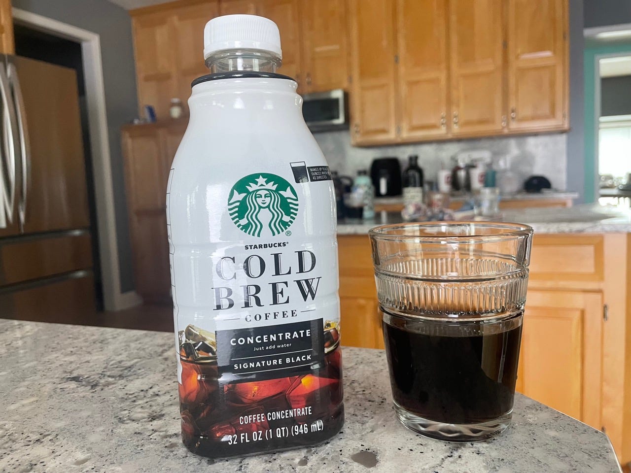 Starbucks cold brew bottle next to glass of cold brew