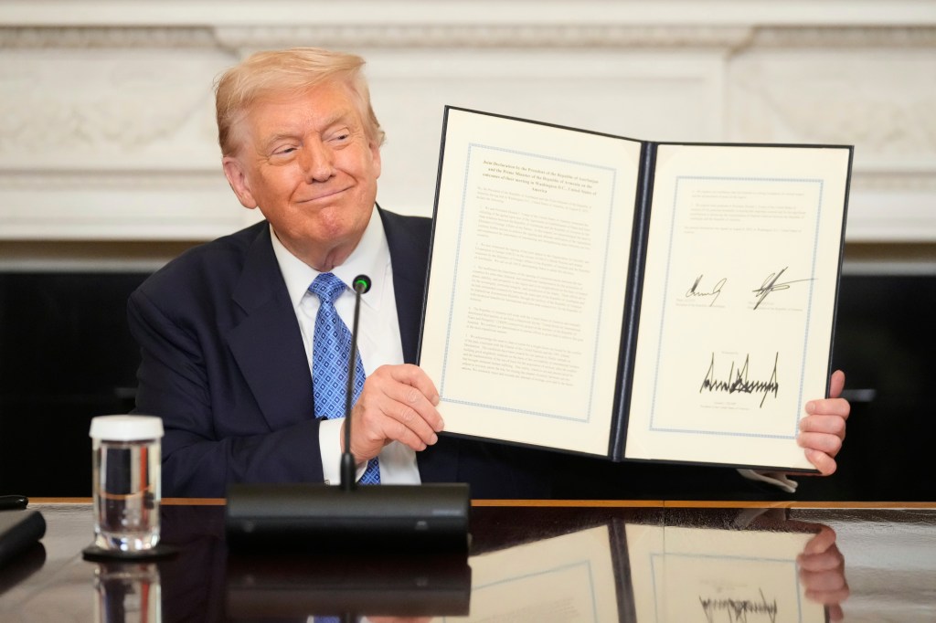 Donald Trump holding a signed document.