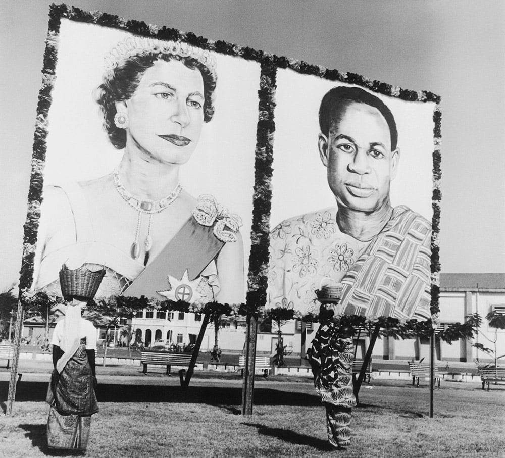 Two women wall past a large billboard with two large images on it.