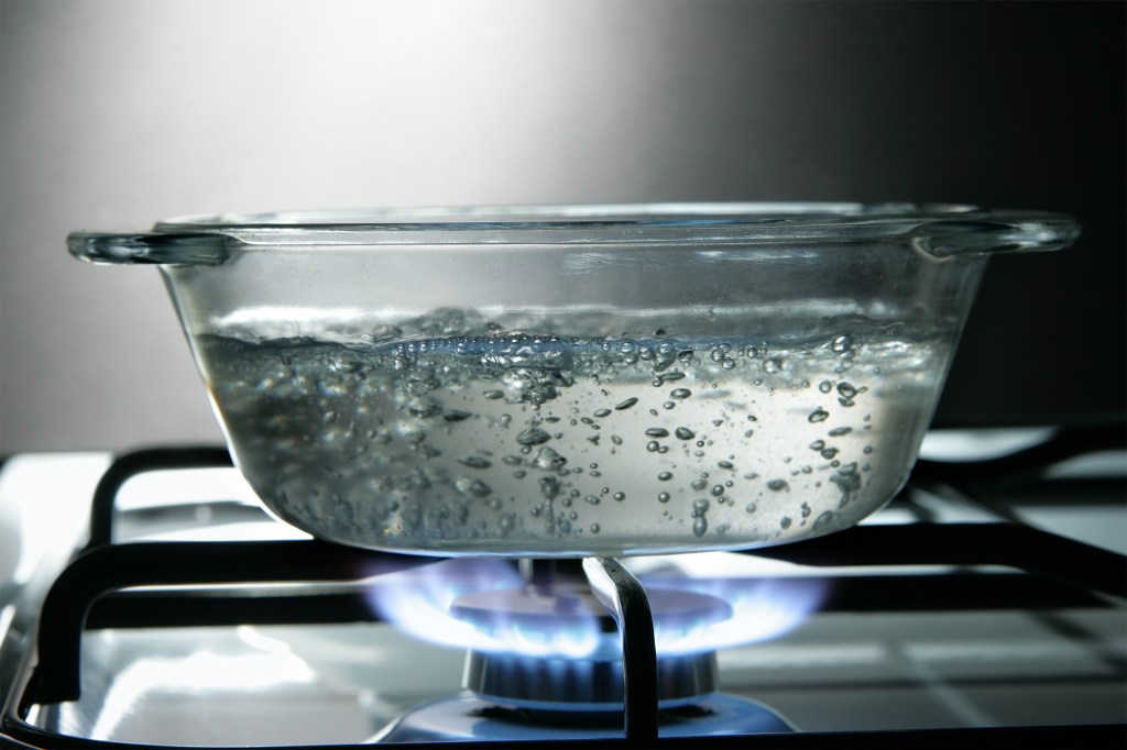 Glass saucepan of boiling water on a gas stove.