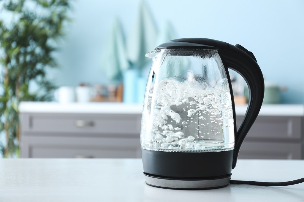 Glass electric kettle boiling water on kitchen counter.