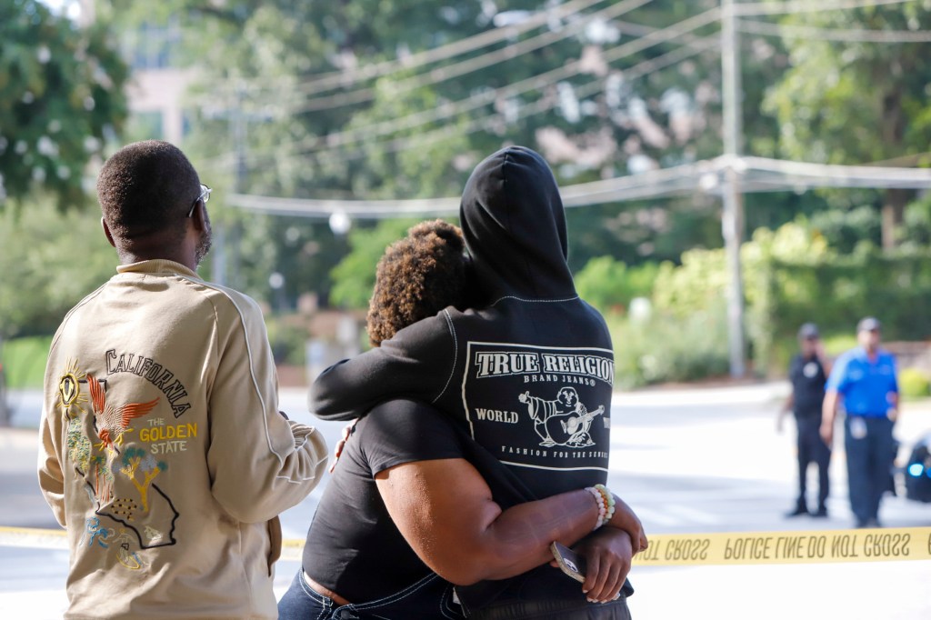 People embracing near police tape at Emory University after a shooting.