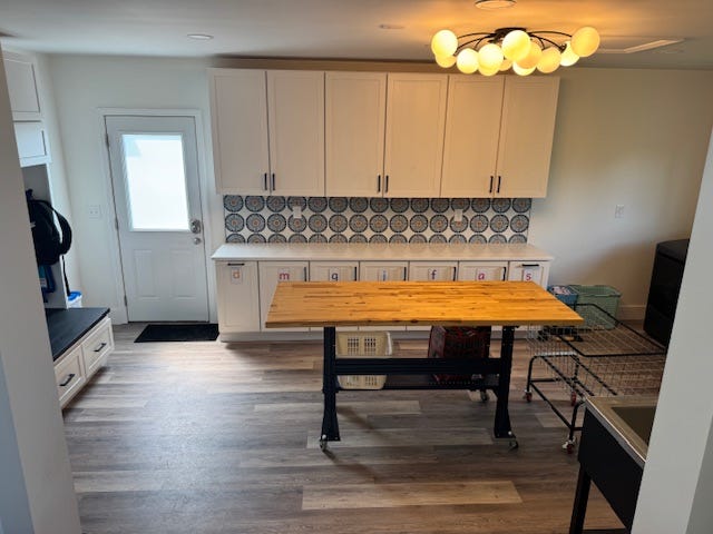 A renovated laundry room with a folding table, cabinetry, and a light fixture.